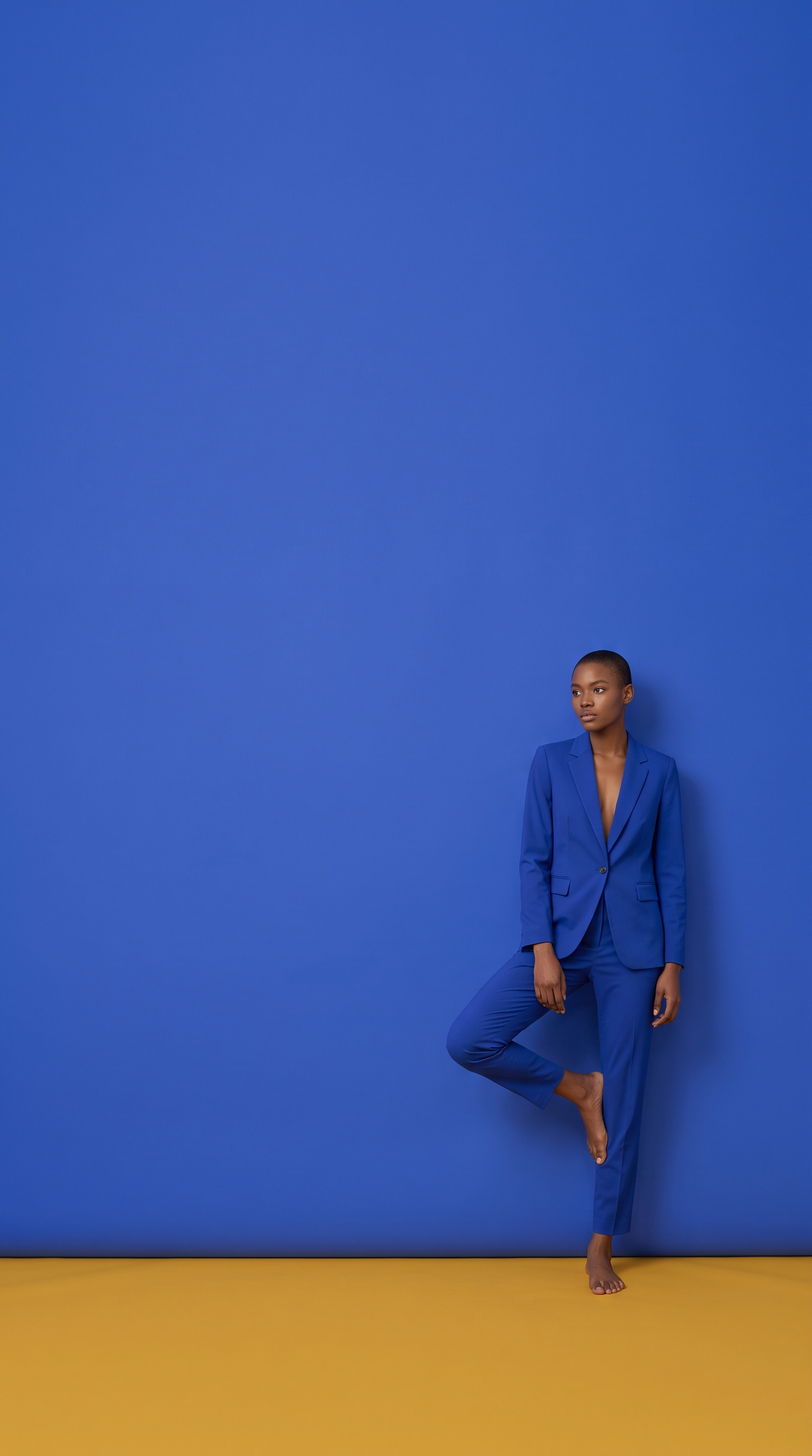 Fashion model in a blue suit against a blue wall